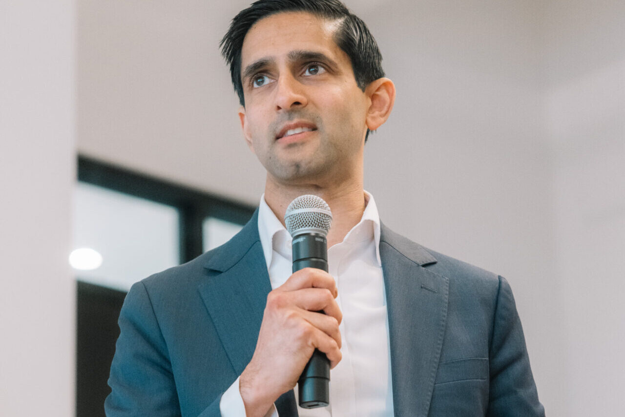 Speaker holding a microphone and note, presenting at the Bluefors Lab opening event.